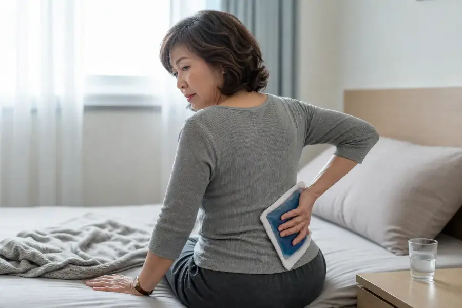 一個人坐著，在下背部貼冰敷袋