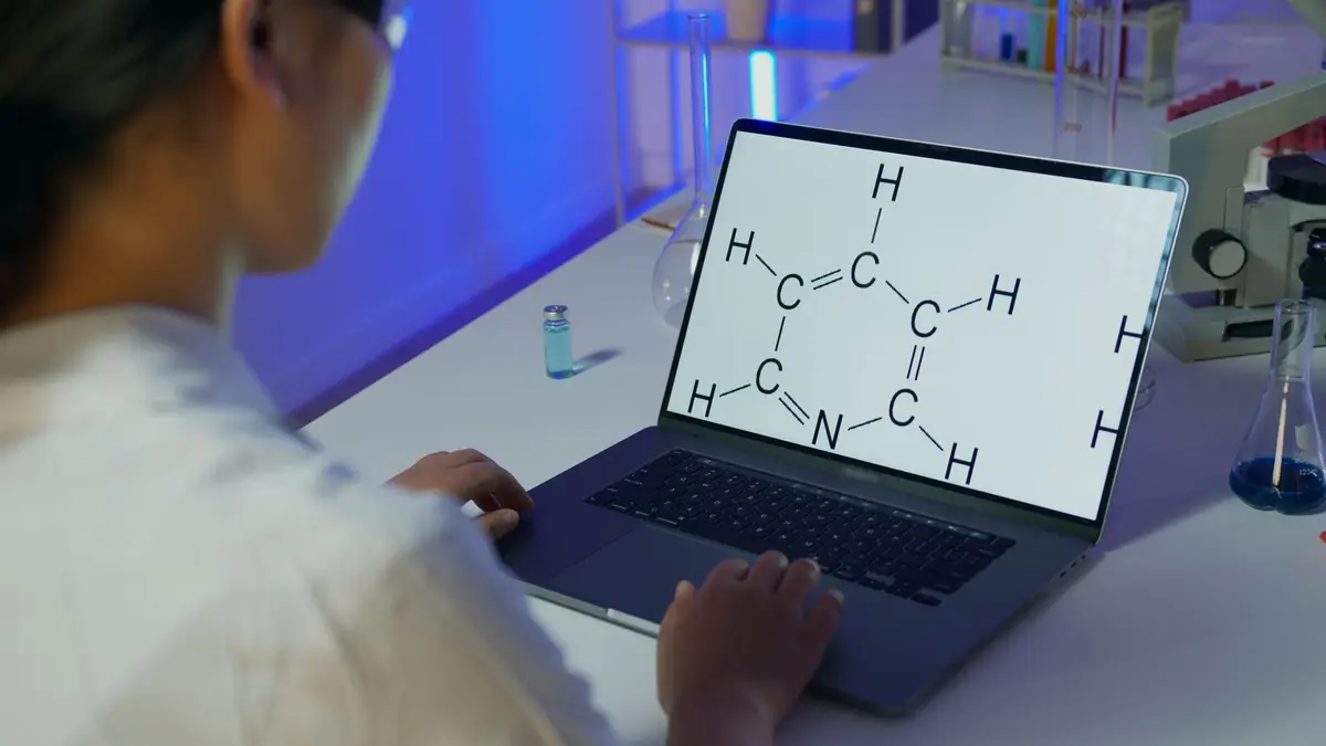 藥廠實驗室裡研究人員在電腦螢幕前檢視分子結構模型，一旁擺放試管與培養皿