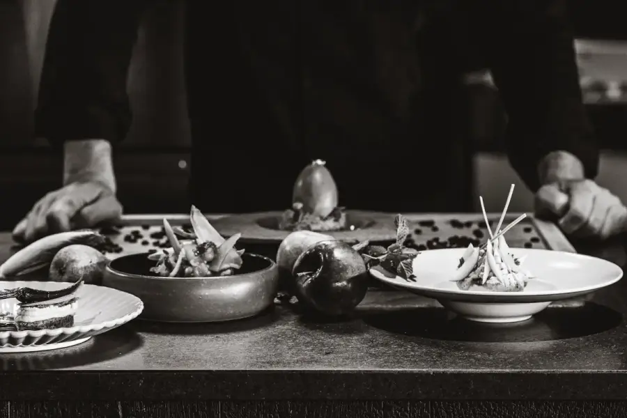 主廚檯面上排開的多道擺盤菜色與當令食材，示意依當日食材決定的菜單