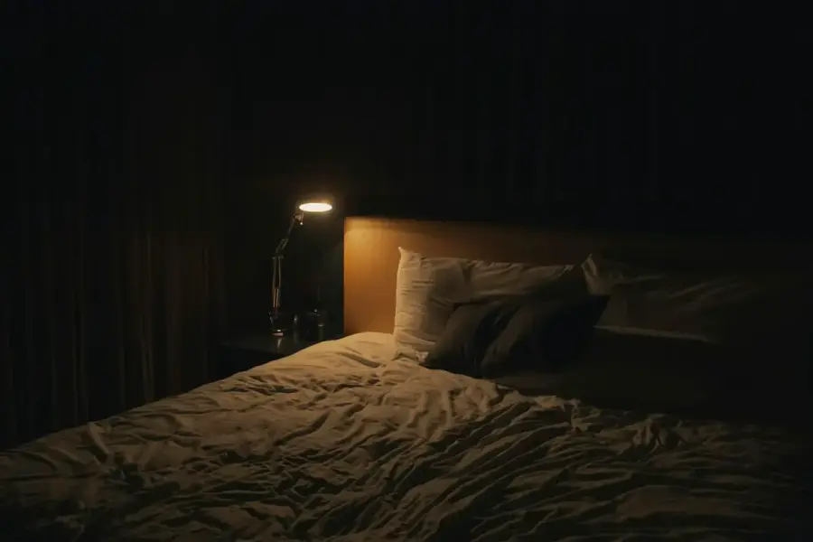 臥室裡的床鋪與床頭燈，睡眠情境示意圖