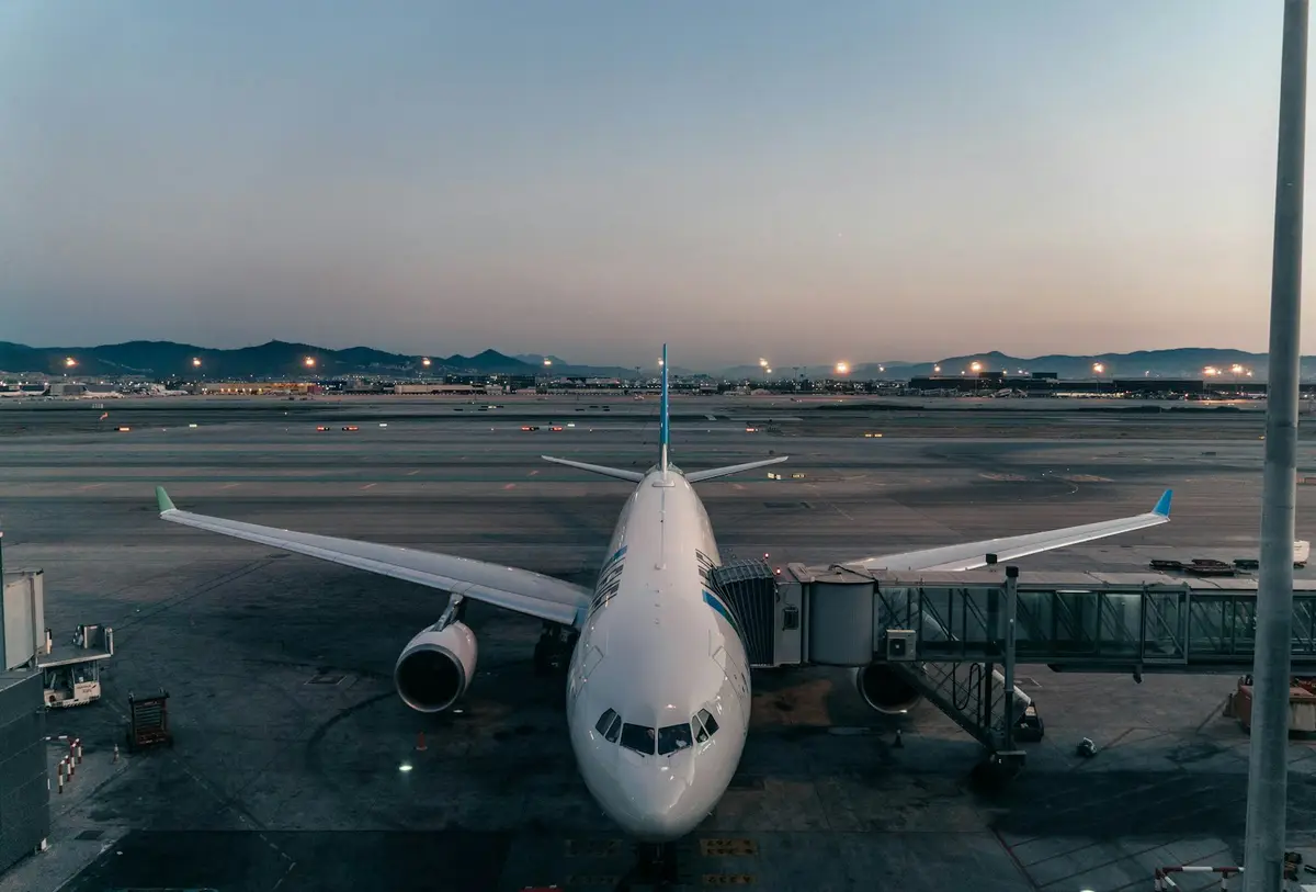 客機停靠在機場空橋旁，機身在夕陽下清晰可見