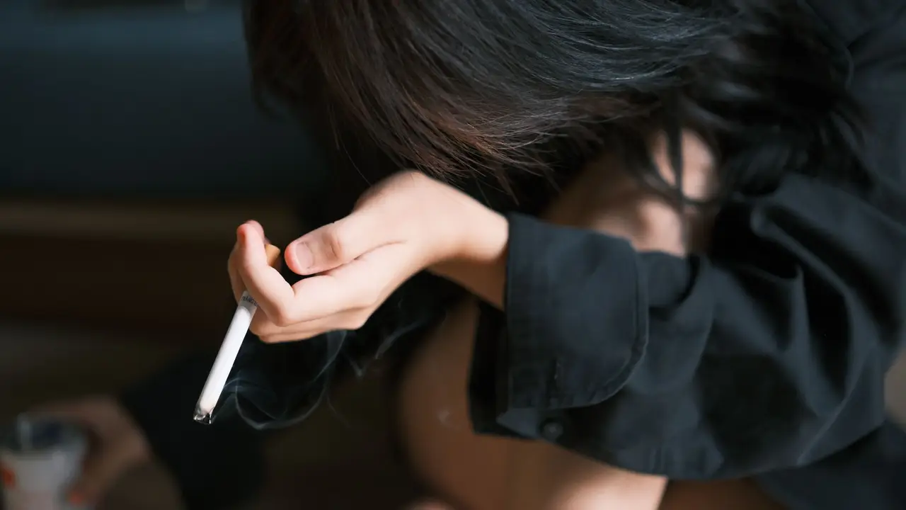 手機螢幕顯示 AI 戒煙聊天機器人介面，旁邊擺放折斷的香菸