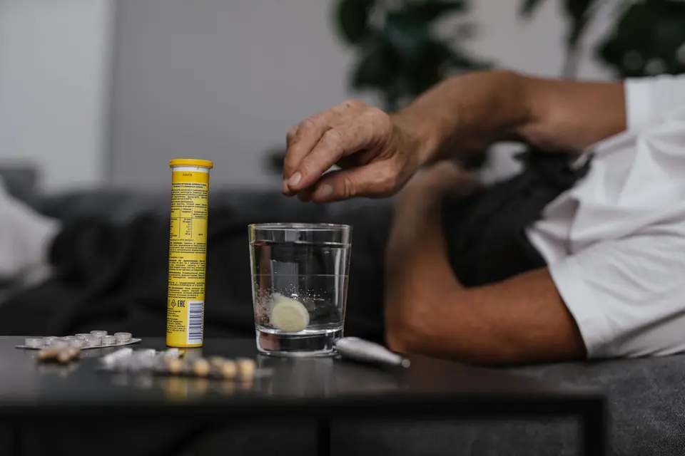 一位長者在家中準備服藥，旁邊放著水杯