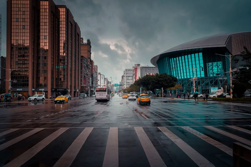 雨天的城市商業街與大型商場建築，路面反射車燈