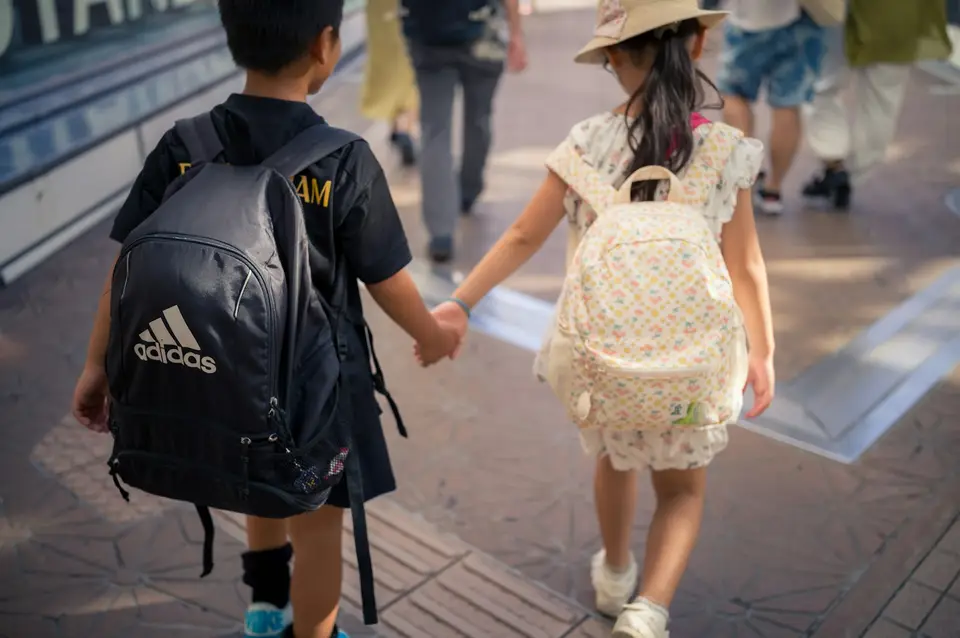 兩名小學生揹著書包並肩走路，象徵書包重量情境