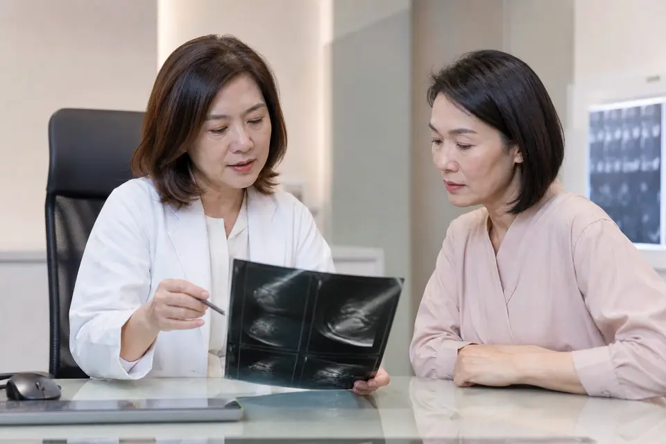 醫師向女性民眾說明乳房攝影與超音波報告示意