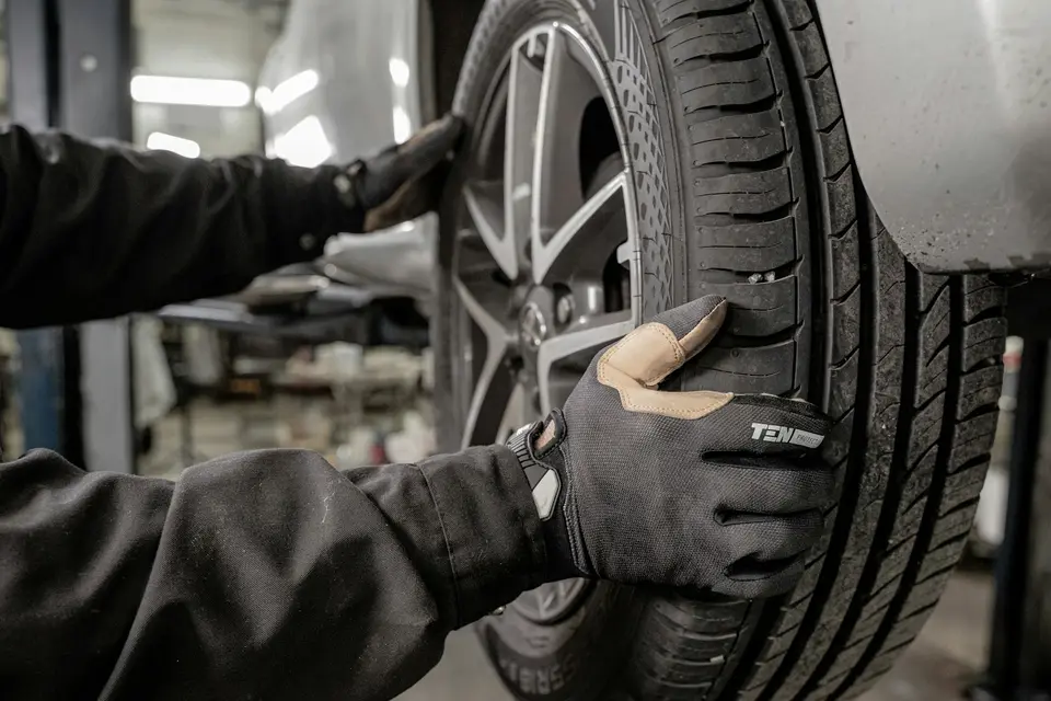 汽車維修人員蹲在保養廠檢查輪胎胎紋