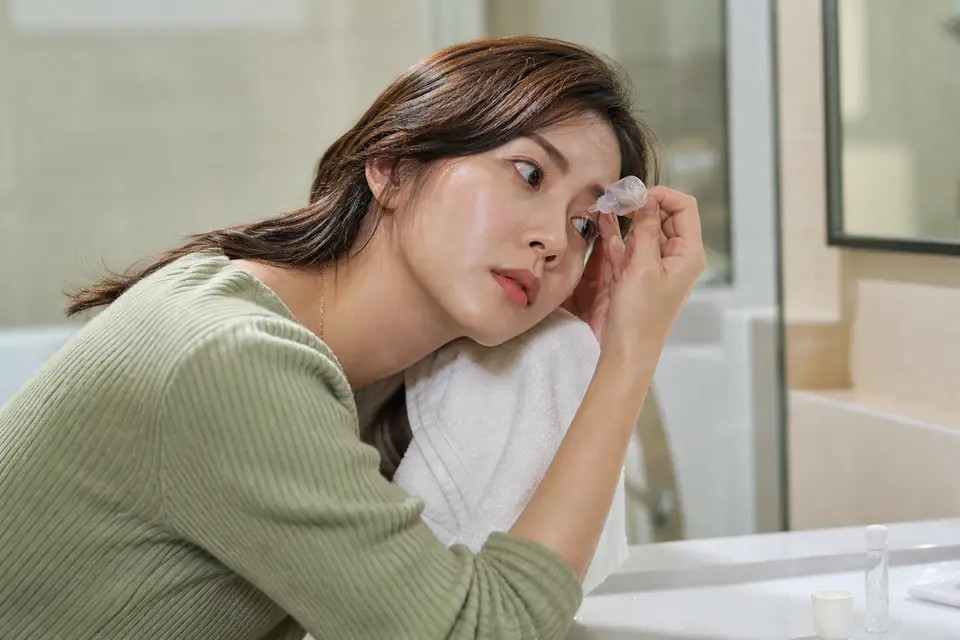 特寫一個人用生理食鹽水沖洗眼睛，示意正確的沖洗方向