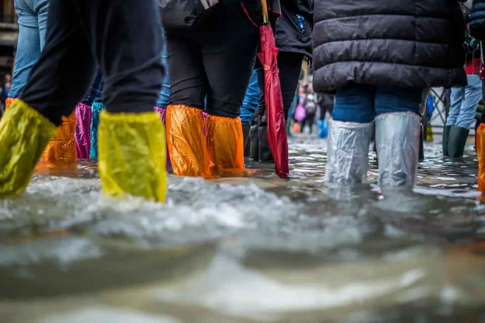 民眾穿著雨具在積水道路中行走，呈現涉水通行的危險情境