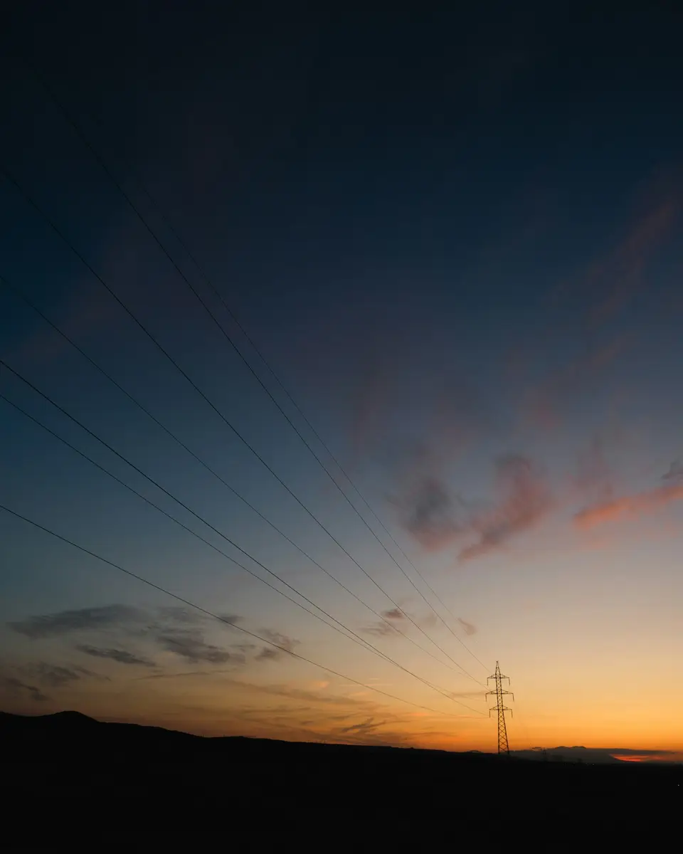 輸電線與夏季天空，象徵高溫下電網與基礎設施承壓