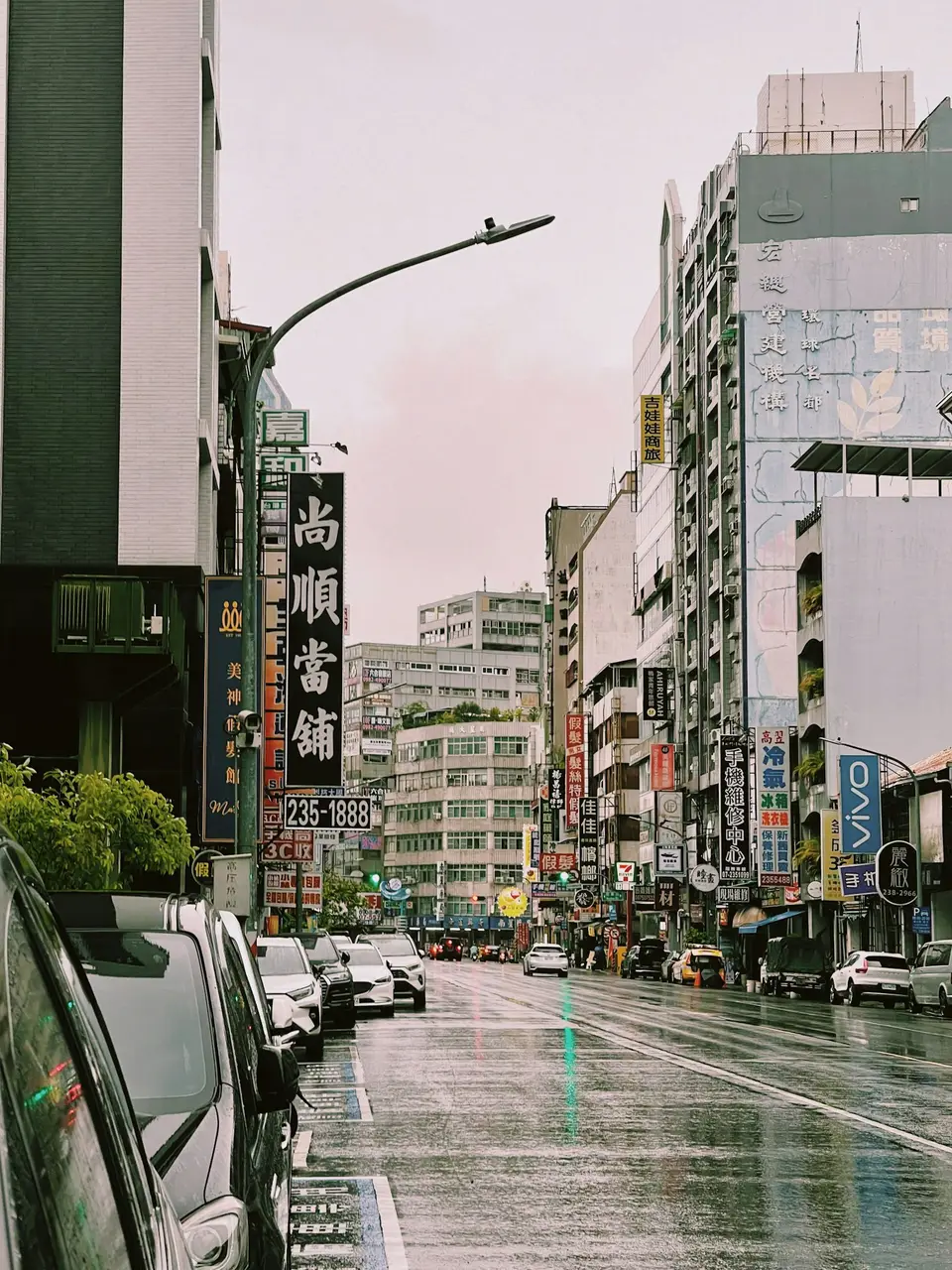 台灣街道在雨中出現積水，兩側有店家與停放車輛